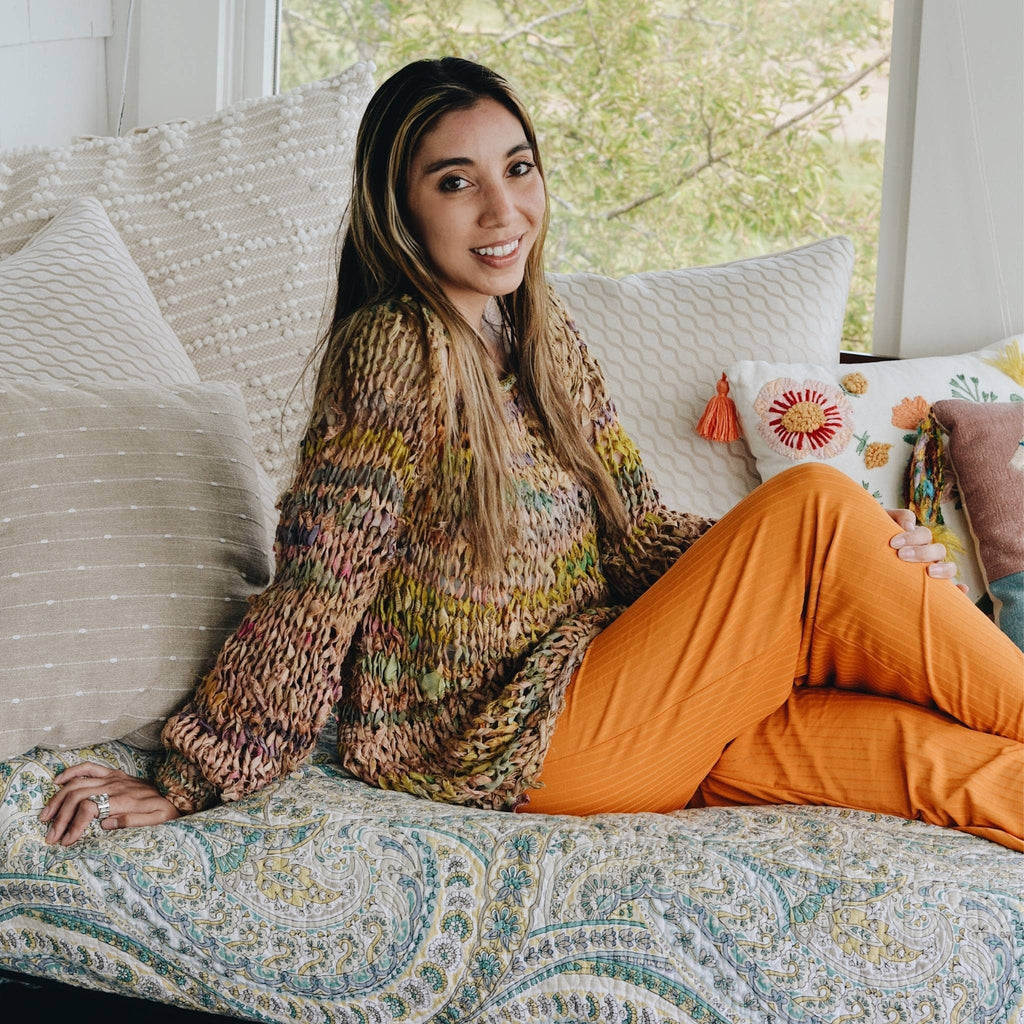 A flat lay view of a bohemian multicolored knit sweater DIY kit with vibrant yarn and a pattern download.