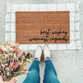 A minimalist brown natural coir doormat with the text Best Wishes, Warmest Regards placed in an entryway.