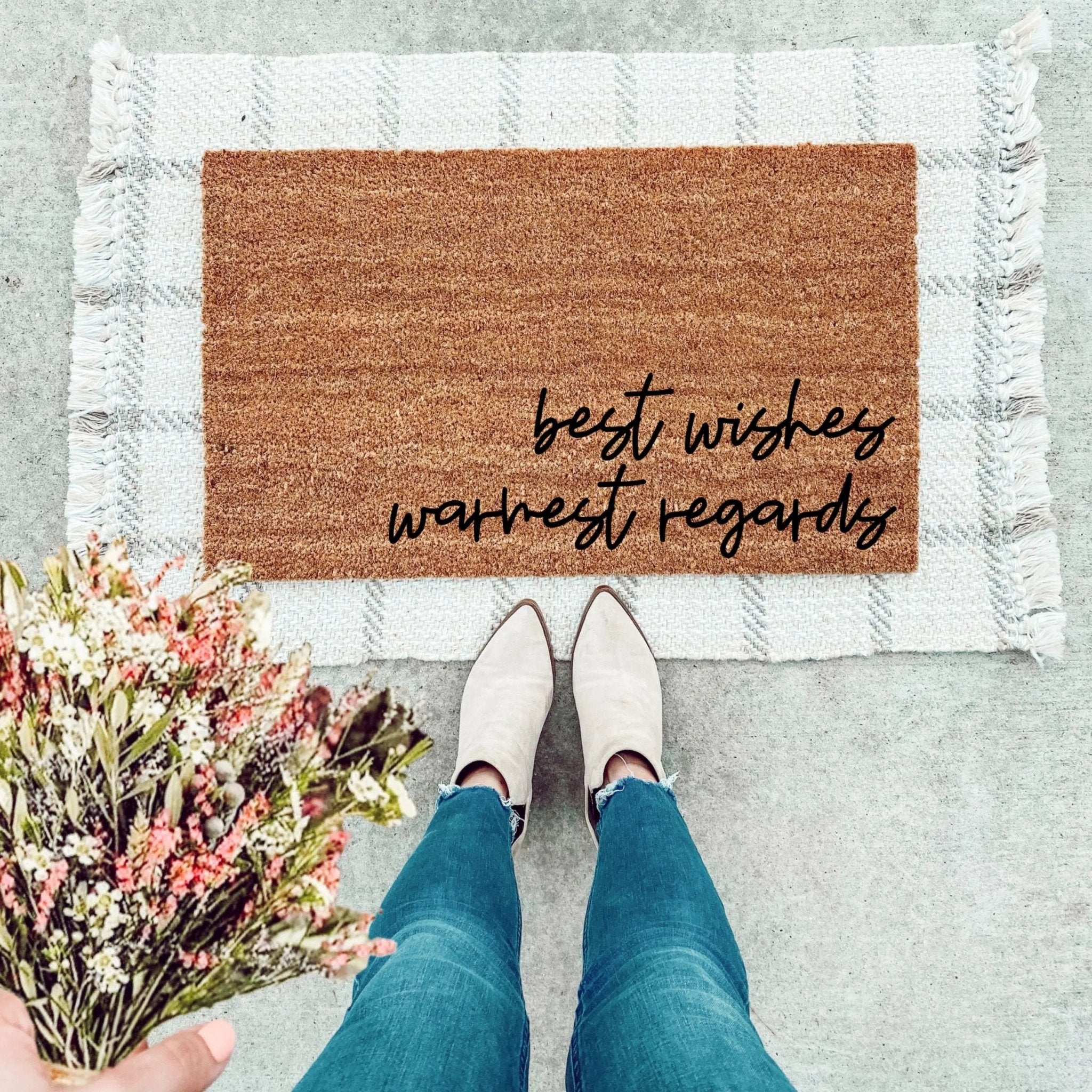 A minimalist brown natural coir doormat with the text Best Wishes, Warmest Regards placed in an entryway.