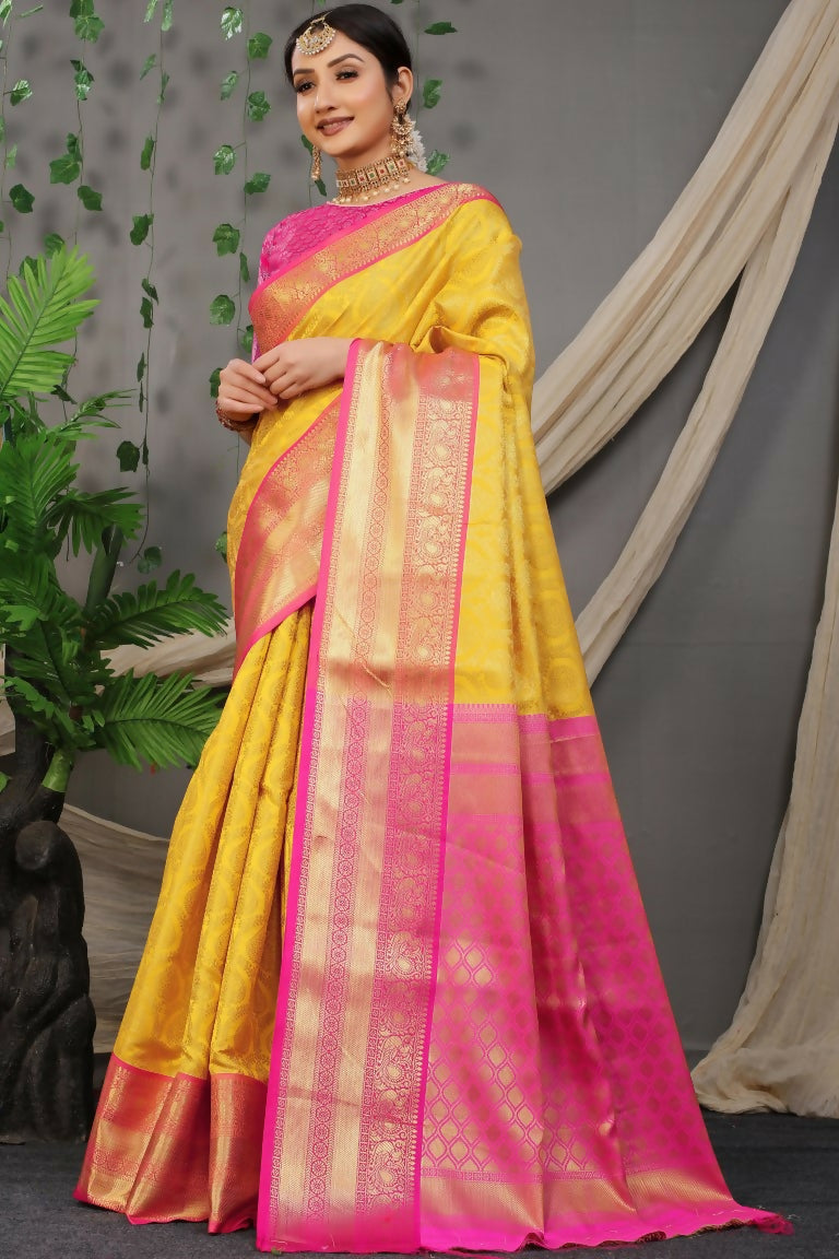 A beautiful Yellow Kanjivaram Silk saree with Zari woven borders and a contrasting pink blouse.