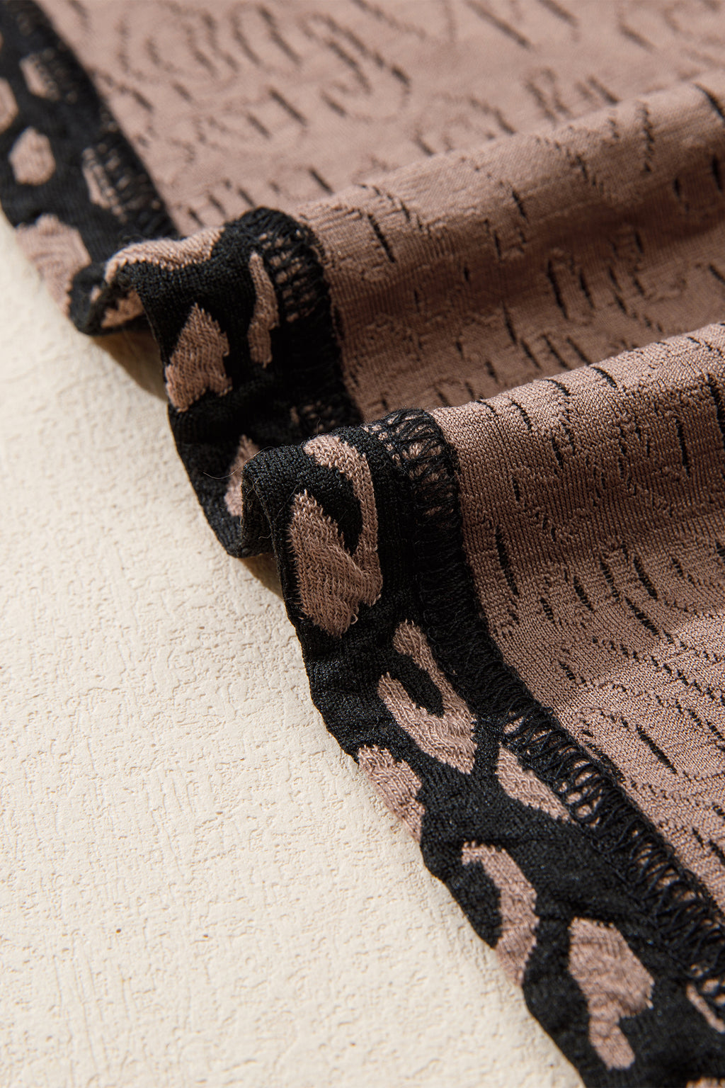 Close-up of textured fabric with black and brown pattern on a beige background