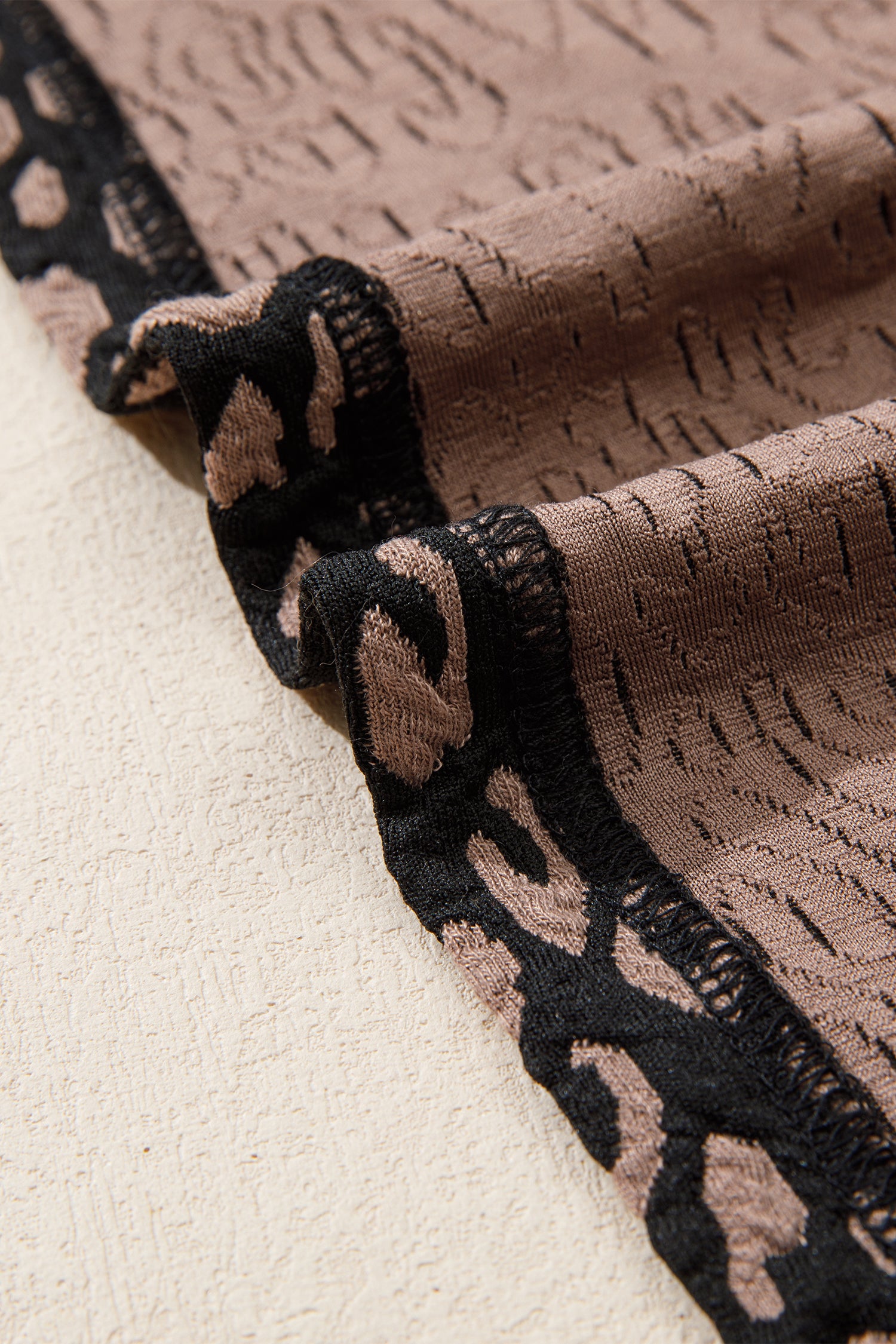 Close-up of textured fabric with black and brown pattern on a beige background
