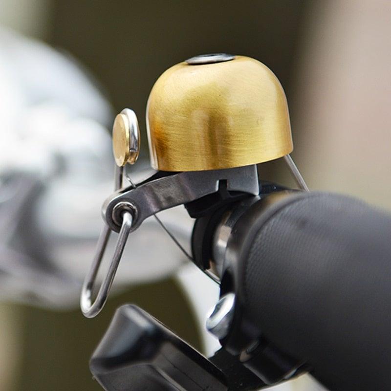 Vintage style brass bicycle bell in gold finish mounted on a bike handlebar