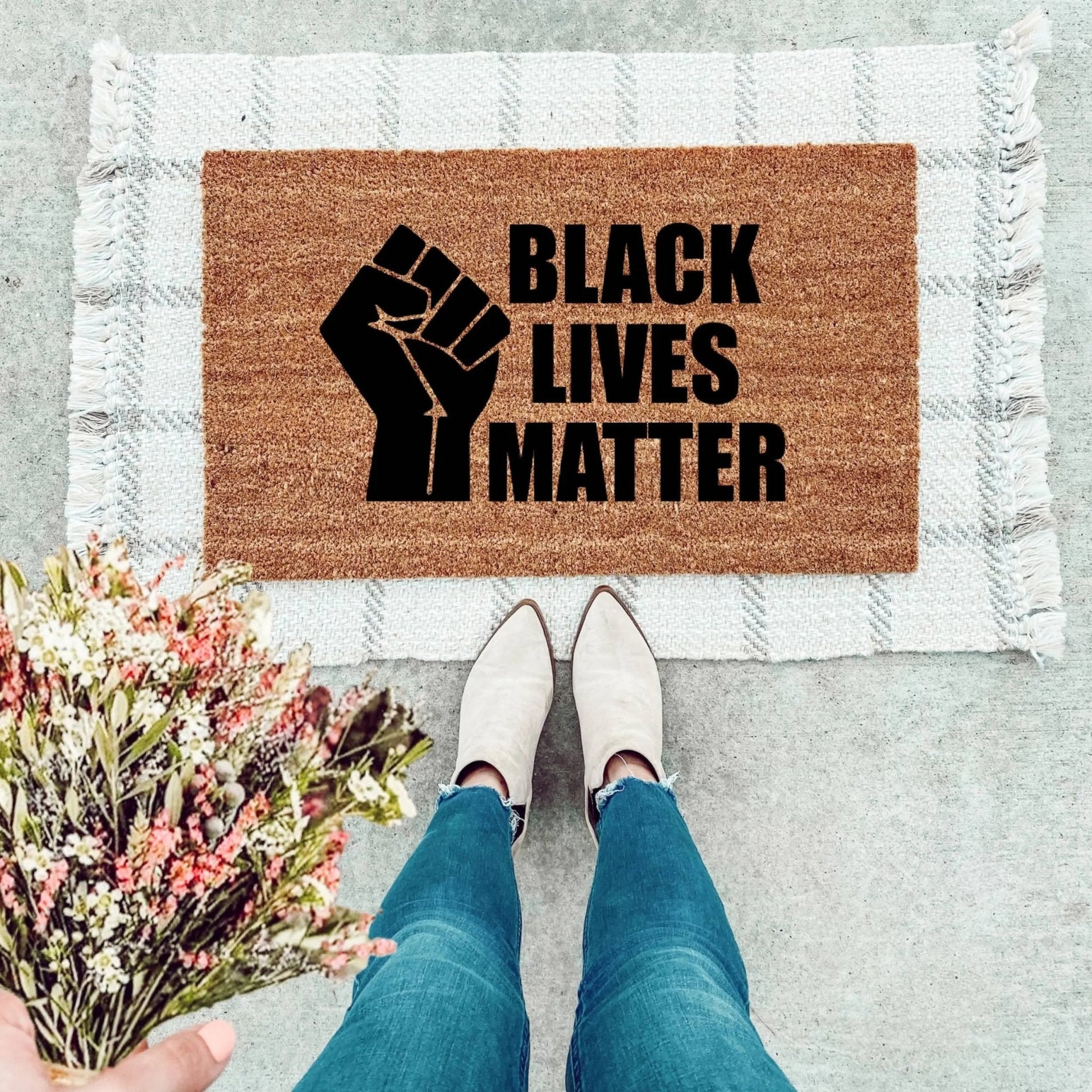 Black Lives Matter text printed on a durable natural coir doormat for front porch entryways.