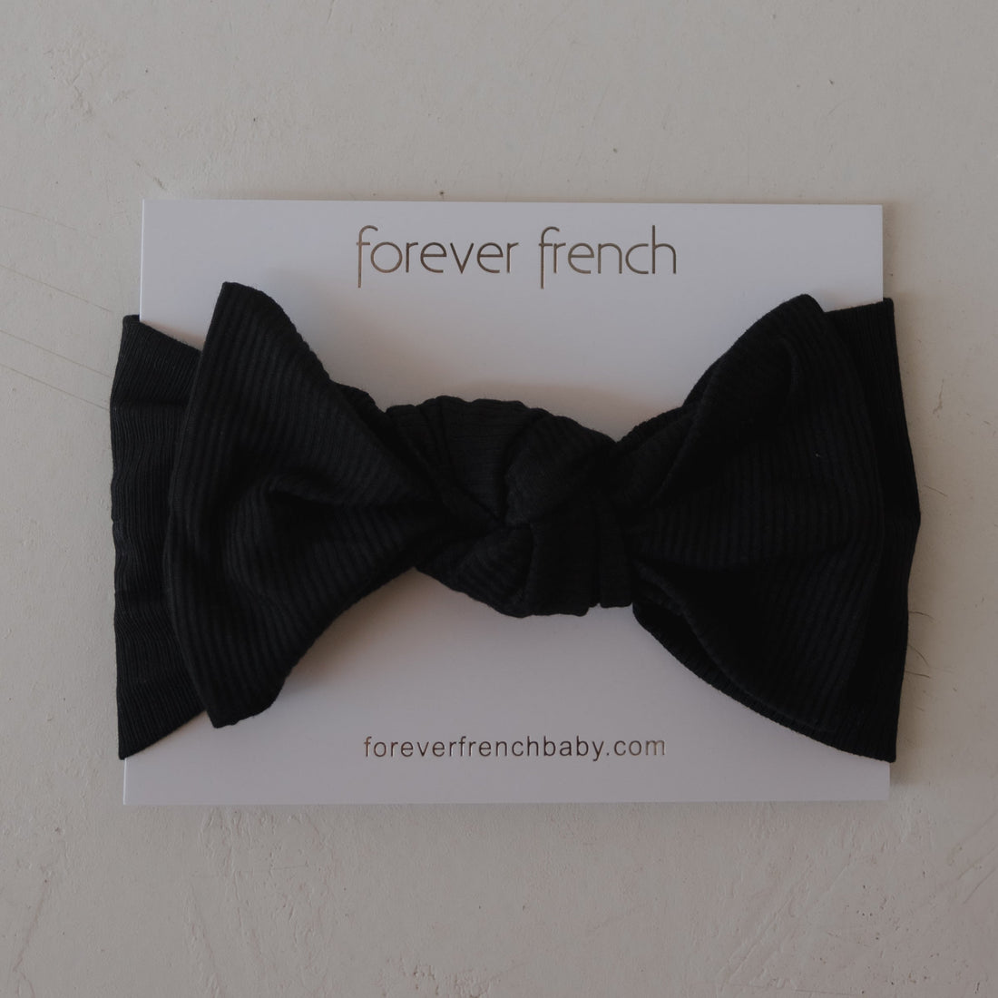 Baby wearing a silky-soft black ribbed bamboo head wrap with a sweet bow detail