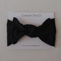 Baby wearing a silky-soft black ribbed bamboo head wrap with a sweet bow detail