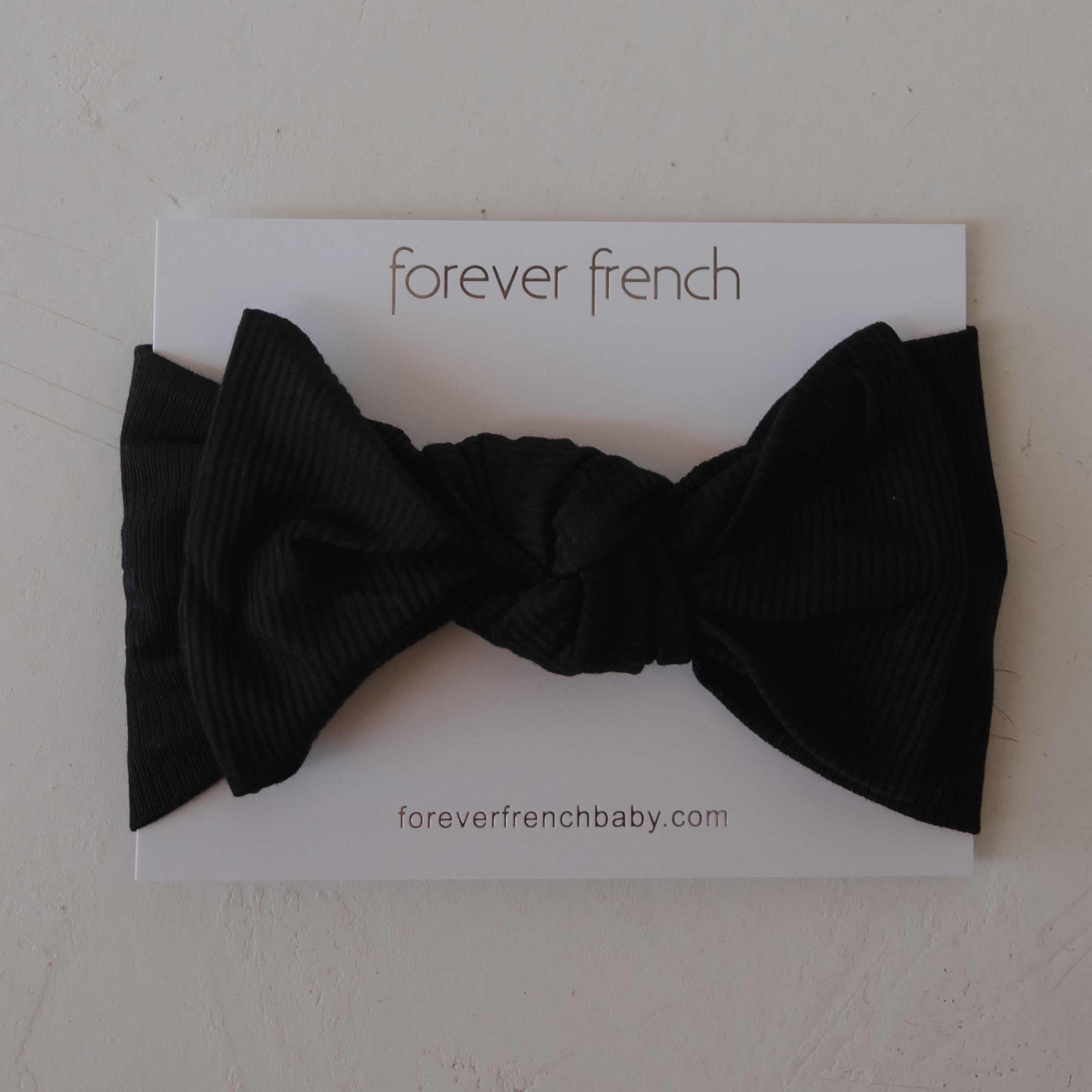 Baby wearing a silky-soft black ribbed bamboo head wrap with a sweet bow detail