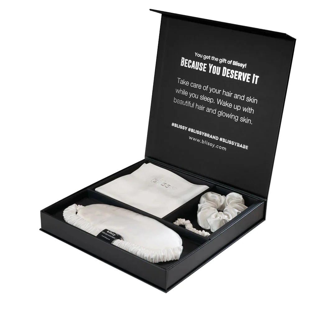 Minimalist white silk pillowcase, sleep mask, and silk scrunchies from the Blissy Dream Set.