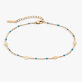 Turquoise enameled chain anklet with gold-plated coin stations on a light background
