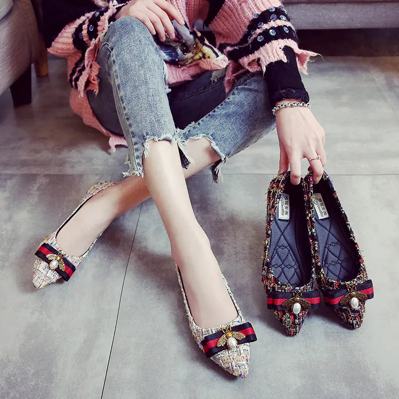 Women wearing beige tweed pointed toe flats with a red and black bow and bee ornament