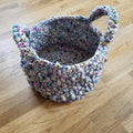 Close-up of a handmade crochet basket featuring bobble stitch texture in a home setting