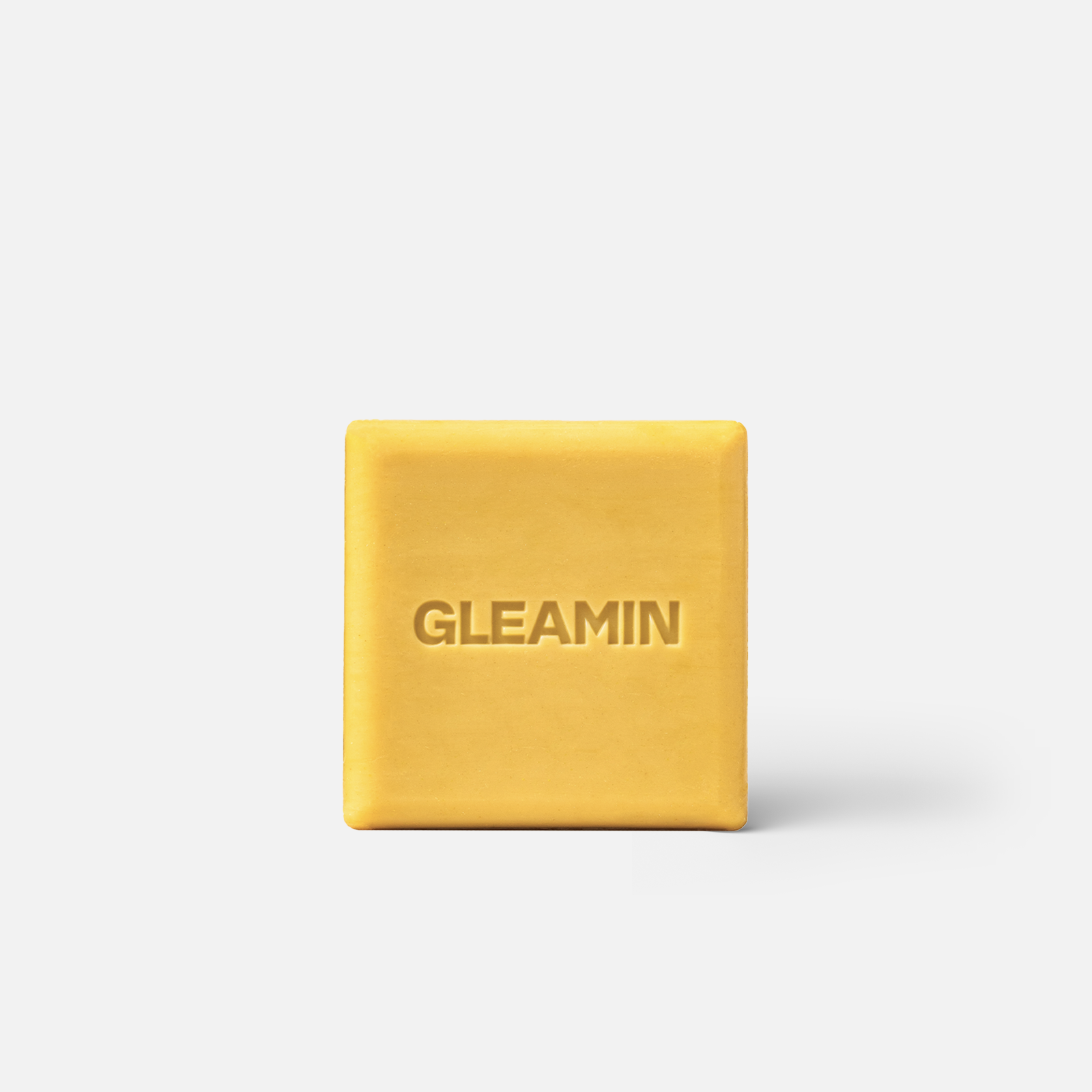 A square yellow Glow Body Bar featuring the Gleamin brand name embossed on the center.