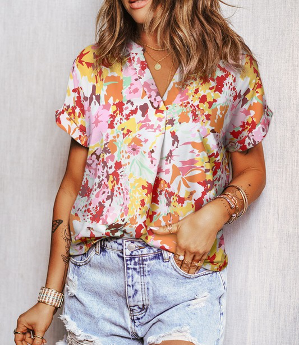 V-neck short sleeve top with a vibrant multi-color floral print on white fabric.