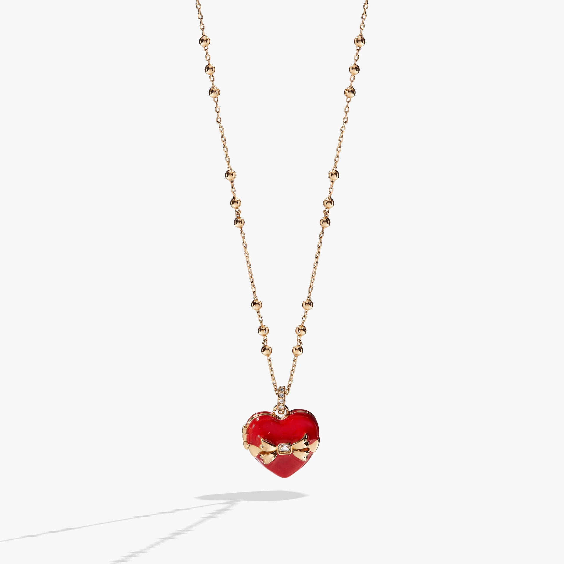 Heart-shaped locket necklace with a crystal bow, opening to reveal chocolate-colored crystals.