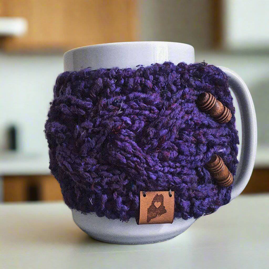 Braided cable knit mug coozie in variegated purple and brown on a ceramic mug