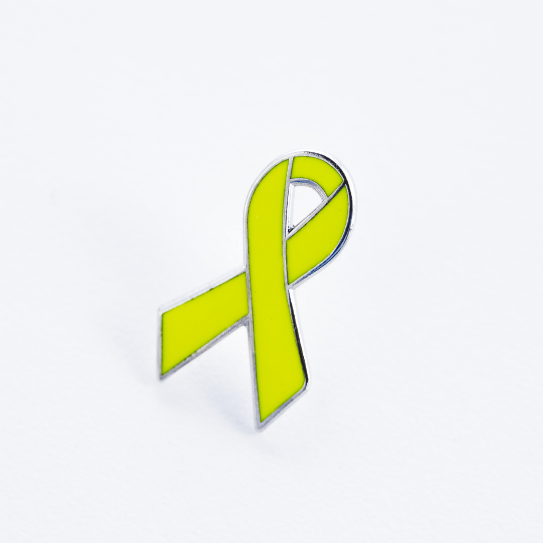 Close up of a yellow awareness ribbon enamel pin with a smooth hard enamel finish on a white background.
