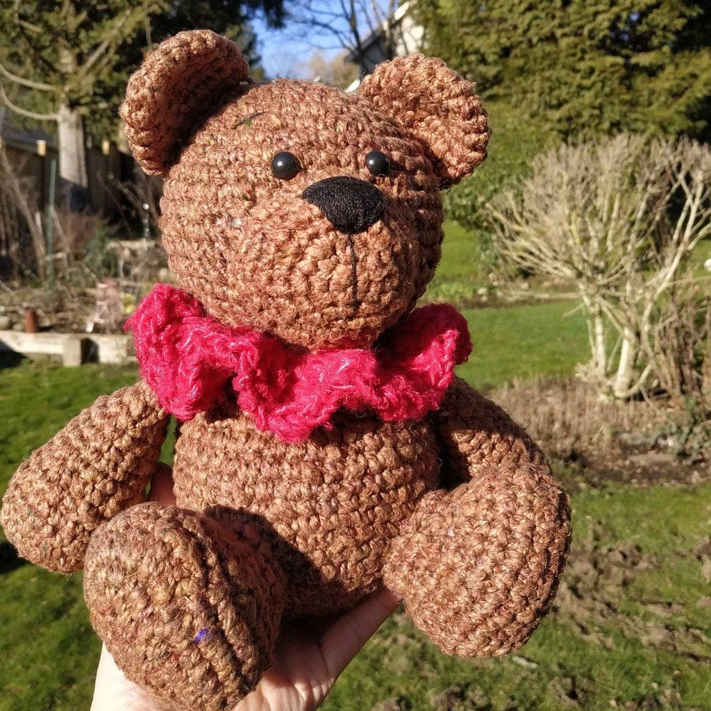 A cute hand-crocheted brown bear amigurumi sitting upright, made with textured tweed yarn.
