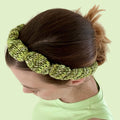 Close up of a hand-knitted bubble pattern headband made from textured silk yarn.