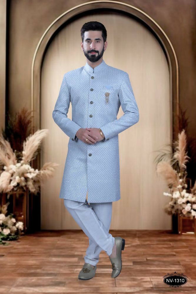 A toddler wearing a blue silk kurta with intricate thread and sequence embroidery and matching pyjamas.