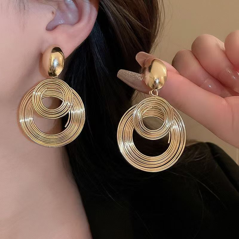 A pair of bold, polished gold statement hoop earrings with a modern minimalist design.