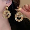 A pair of bold, polished gold statement hoop earrings with a modern minimalist design.