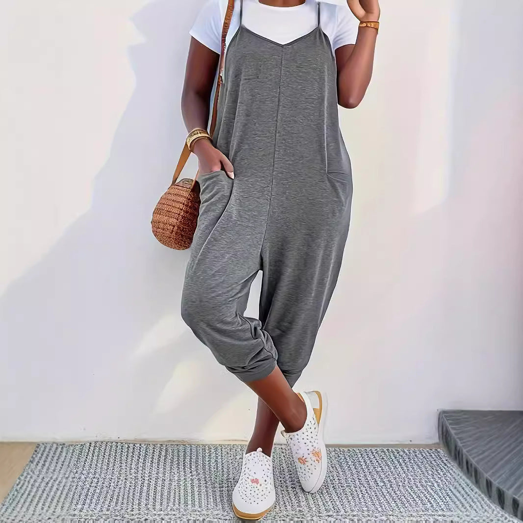 A woman wearing a loose casual sling jumpsuit with pockets in a neutral color
