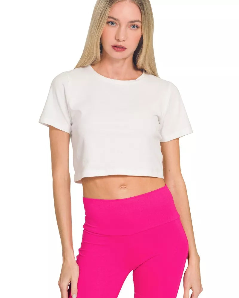 Woman wearing a white crop top and pink shorts on a white background