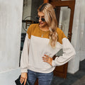 A woman wearing a mustard and beige color-blocked long-sleeve fleece pullover with a round neck.