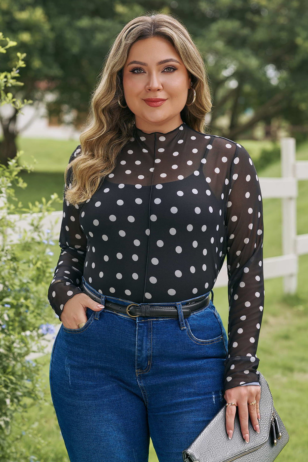 Woman wearing a black and white polka dot mesh long sleeve colorblock top with a stand neck.