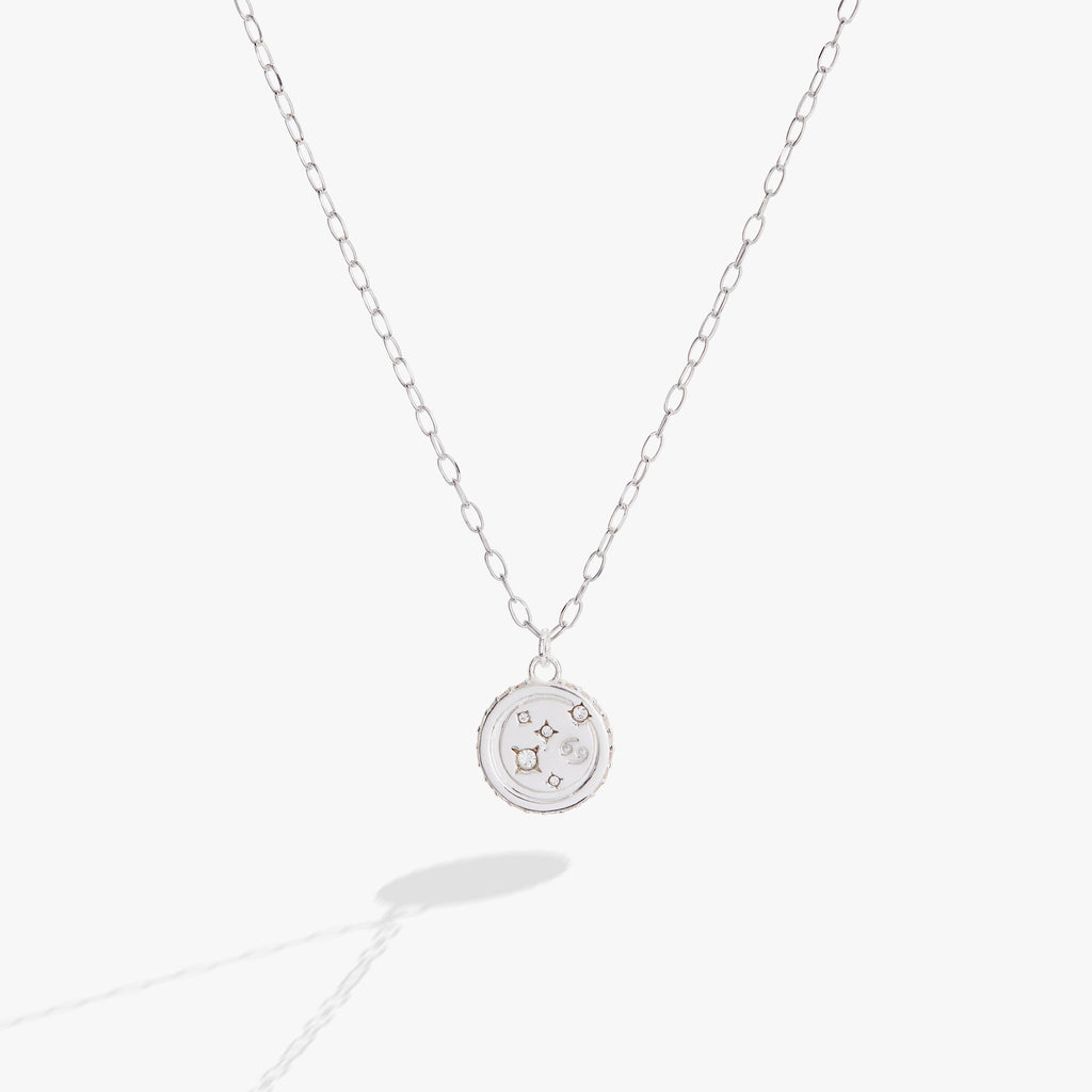 Close up of a Cancer zodiac charm necklace in polished sterling silver with crystal accents on a cable chain.