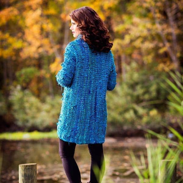 Close up of vibrant ocean blue and teal textured knit fabric on a completed high-low turtleneck sweater