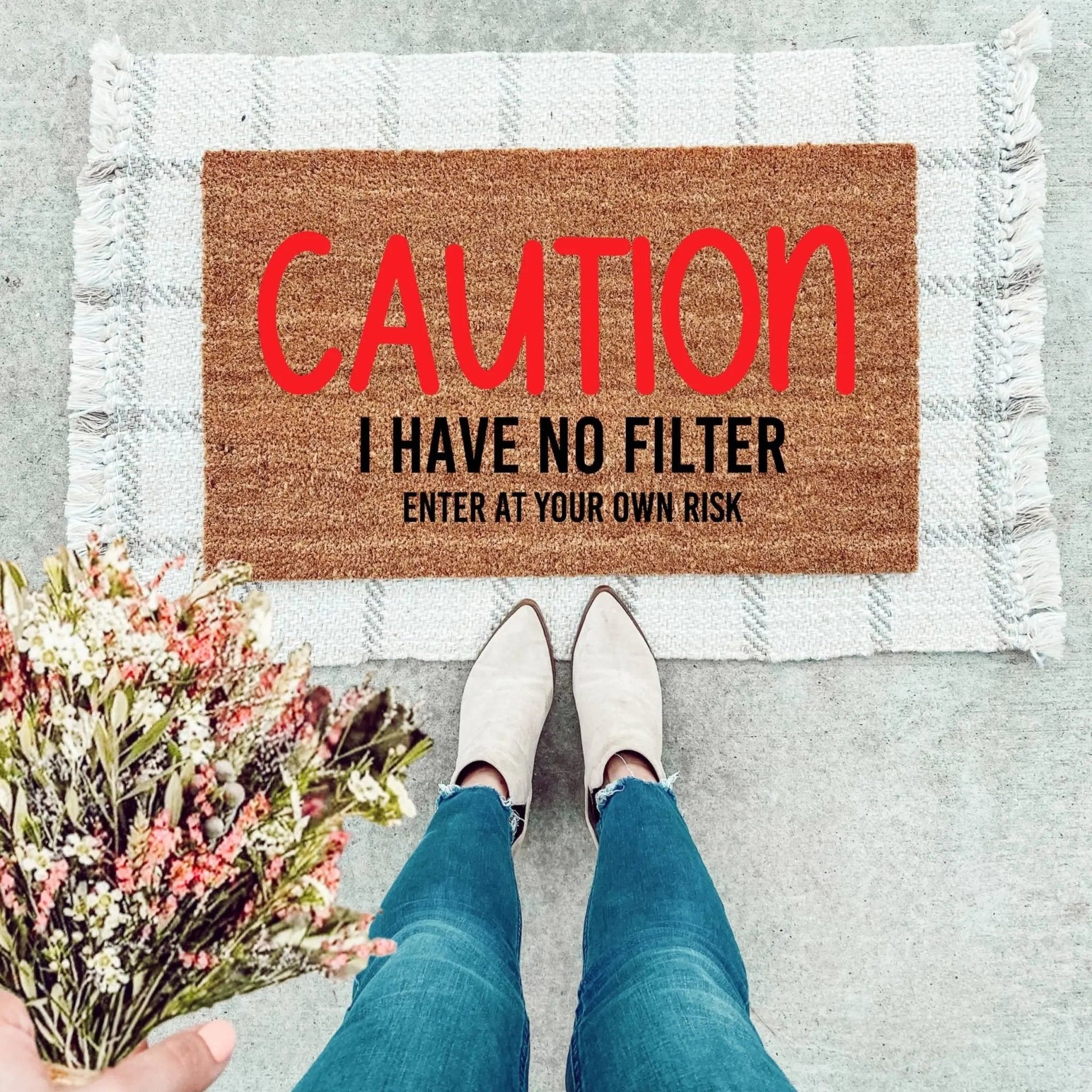 A modern coir doormat in brown with black and red text reading Caution! I Have No Filter.