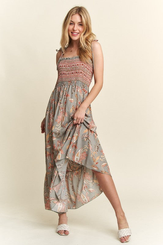 Woman wearing a floral smocked cami dress with tie shoulders in sage-green