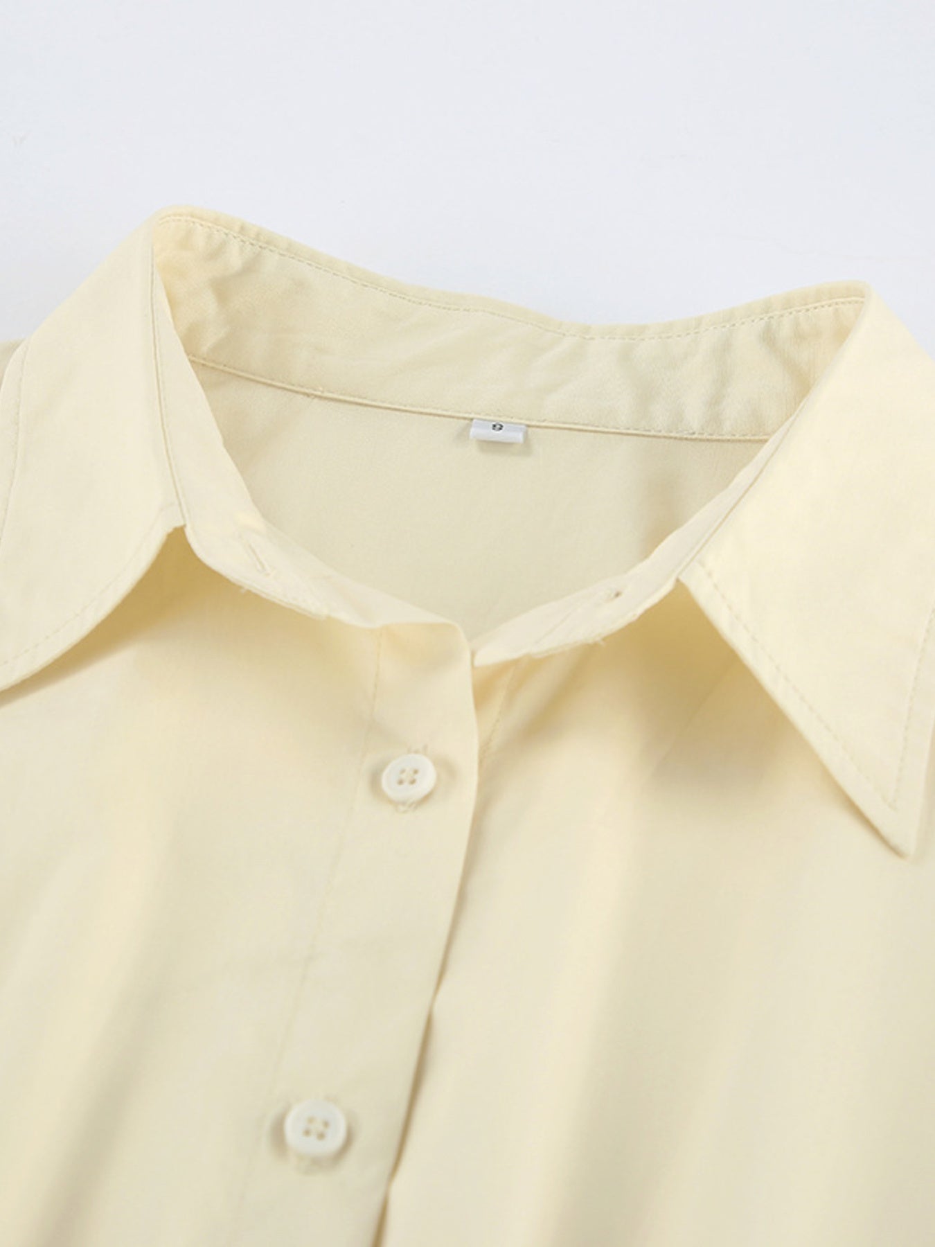 Close-up of a light yellow shirt with buttons on a white background