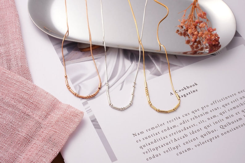 Minimalist Morse Code custom name necklace with delicate metallic detailing.