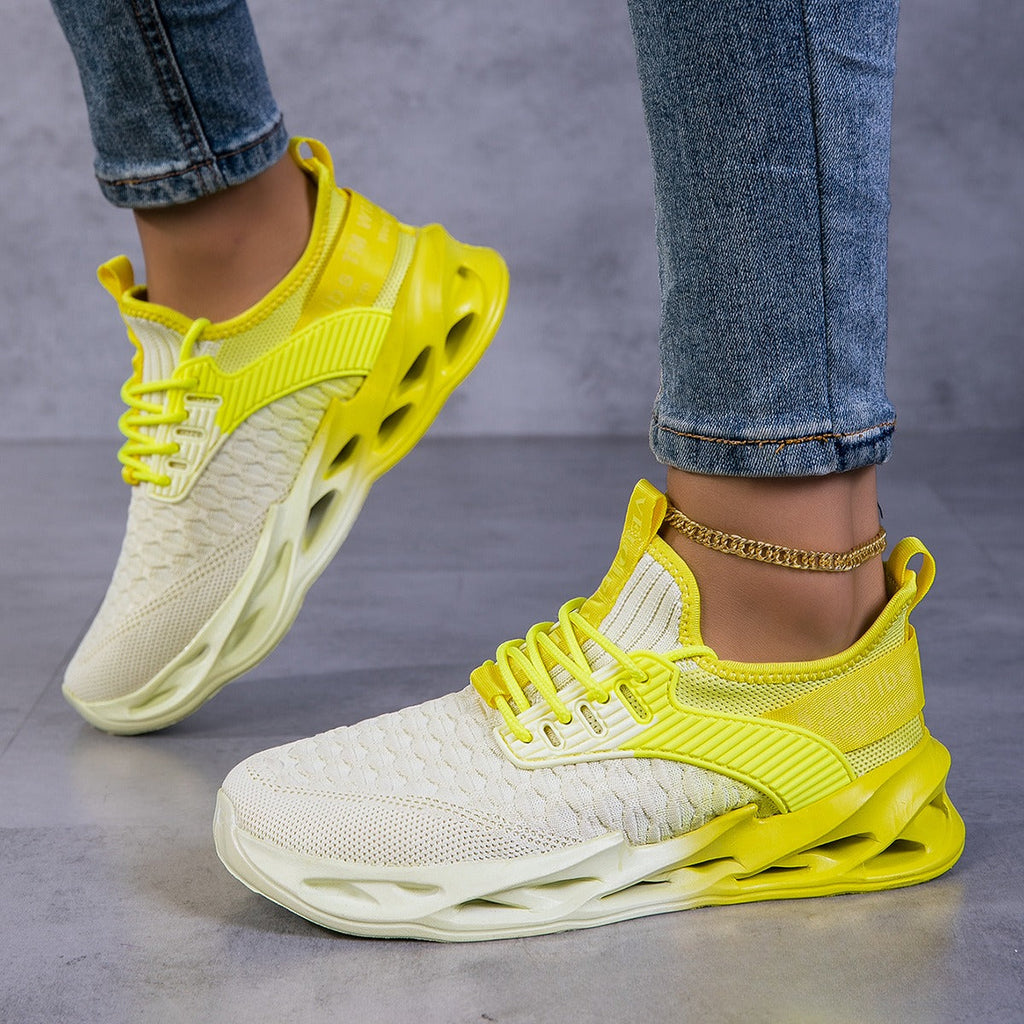 A pair of yellow and pink sporty knit running sneakers on a gray surface