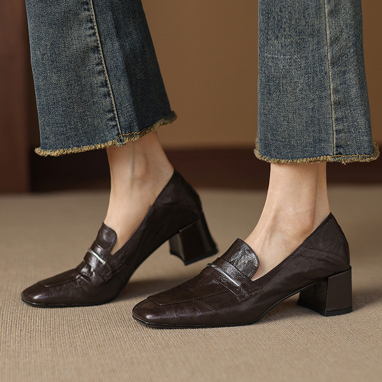 Close up of a pair of brown sheepskin leather square toe chunky heel pumps being worn with denim jeans.