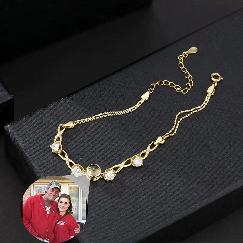 Close-up of a minimalist infinity symbol bracelet featuring a central photo projection charm.