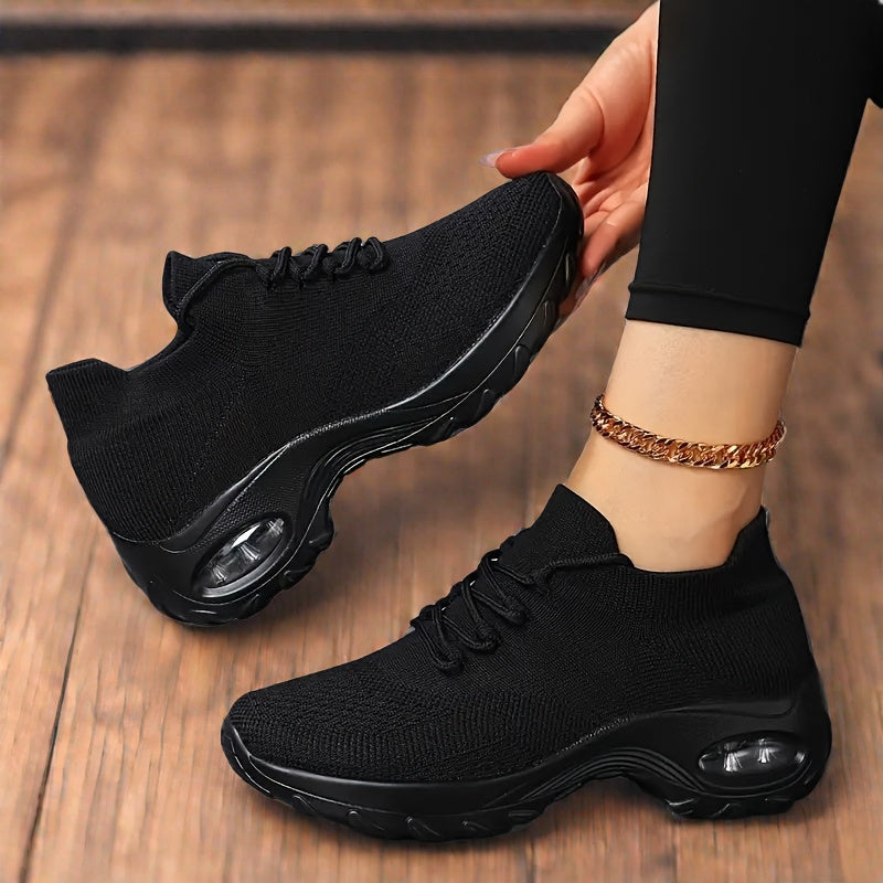 A person wearing black lightweight sneakers with arch support and a visible air cushion sole.