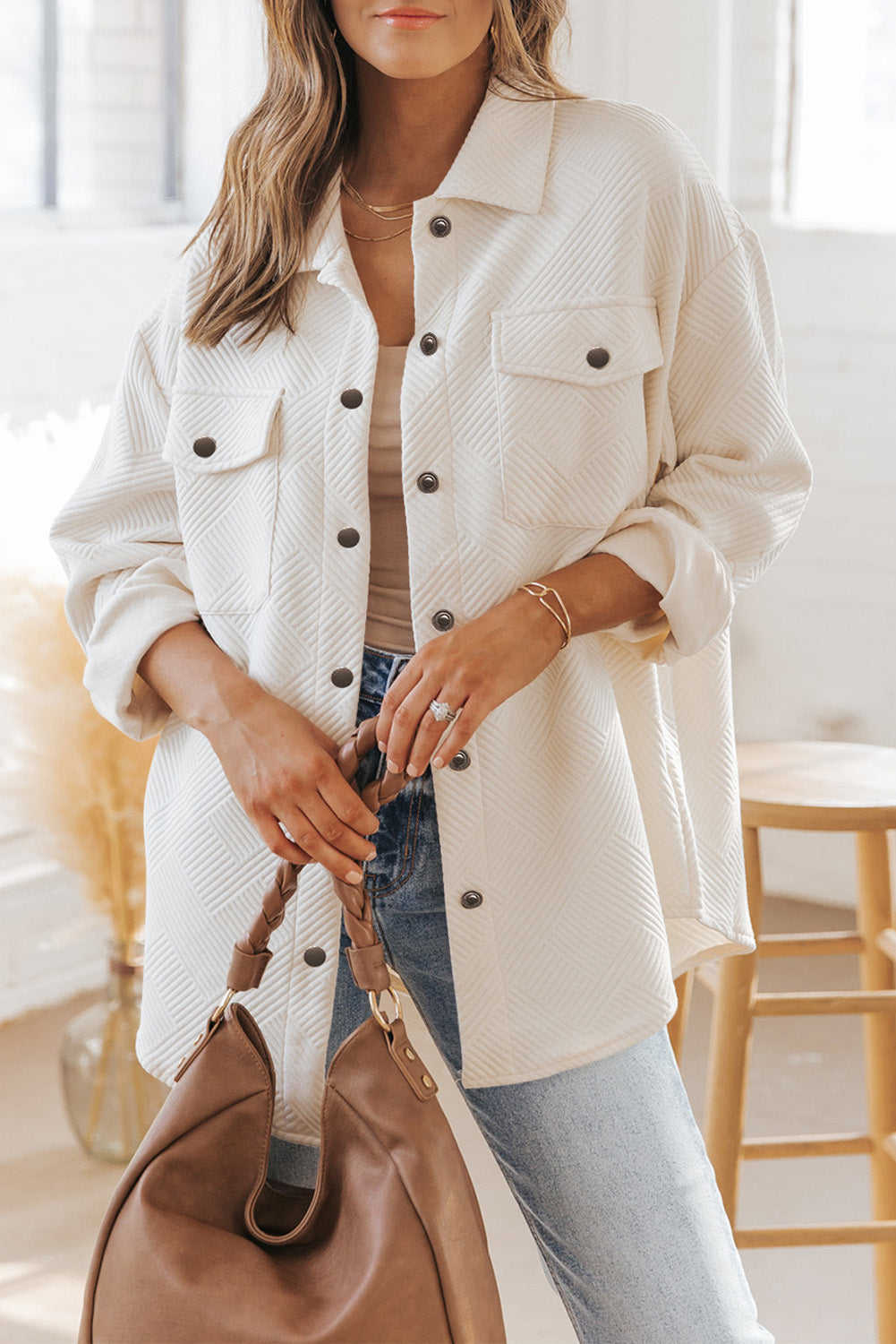 Woman wearing a white textured long-sleeve button-down shacket with flap pockets