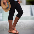 Woman wearing solid black high-rise slim fit cropped leggings in a minimalist sporty style.