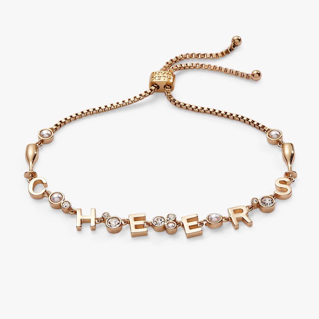 Cheers charm bolo bracelet featuring champagne flutes, pearl crystals, and gold-tone beads