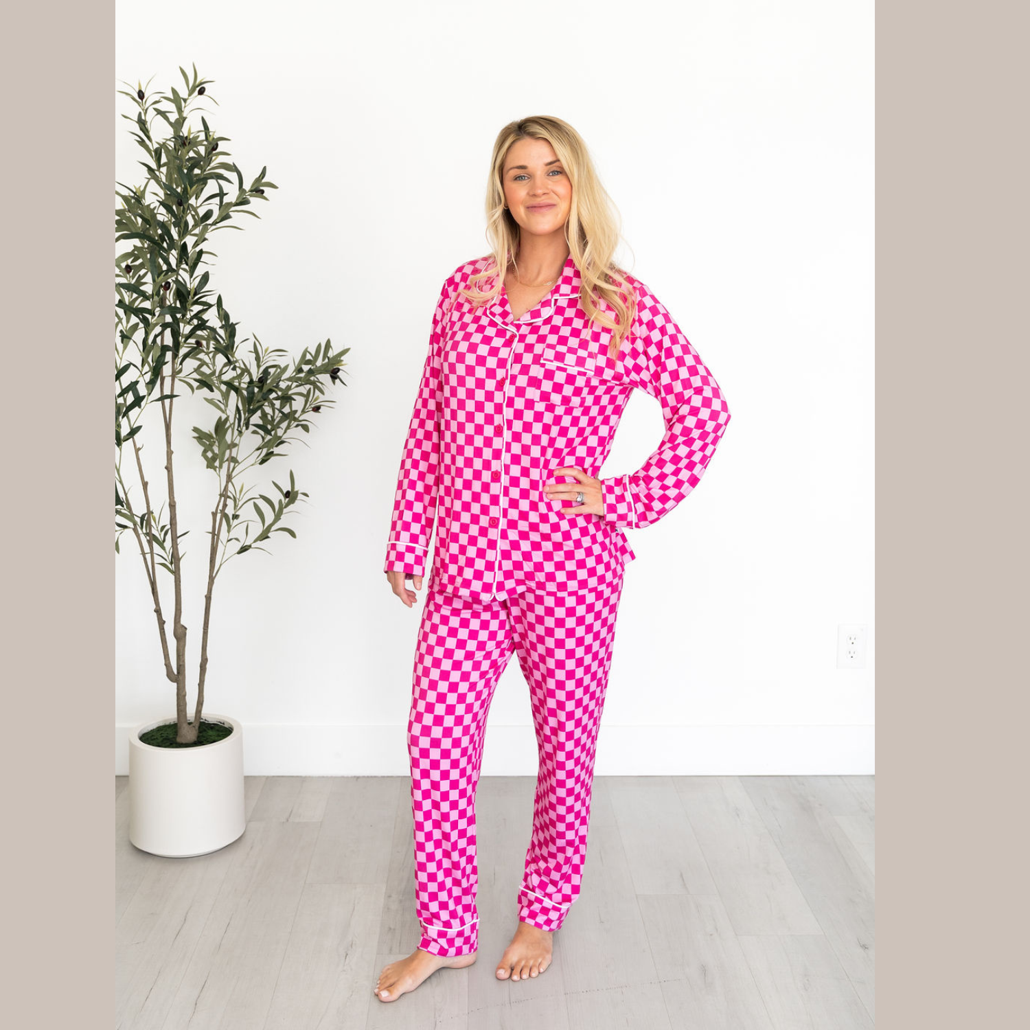 Woman wearing a bright pink and white checkerboard print button-up long sleeve pajama set.
