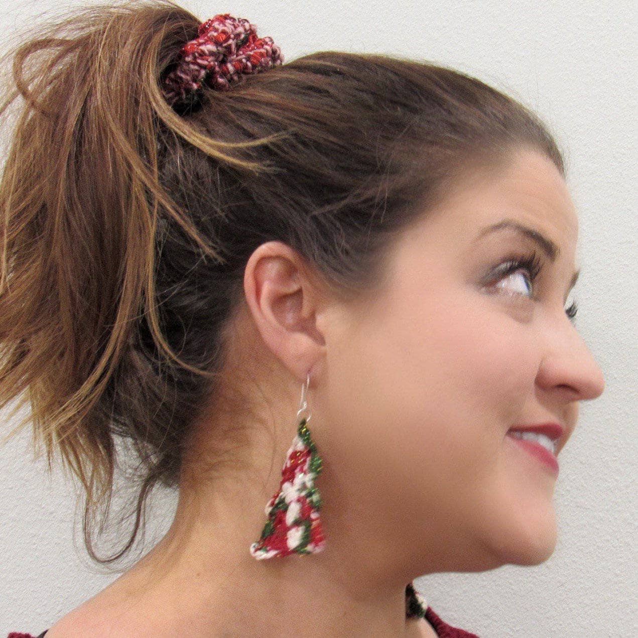 Close up of handmade crochet Christmas tree earrings made with Holly Holly silk yarn.