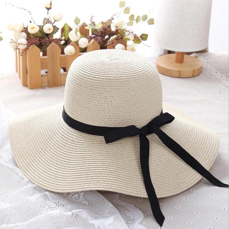 A stylish girls wide-brim straw sun hat with a black ribbon trim for summer beach outings.