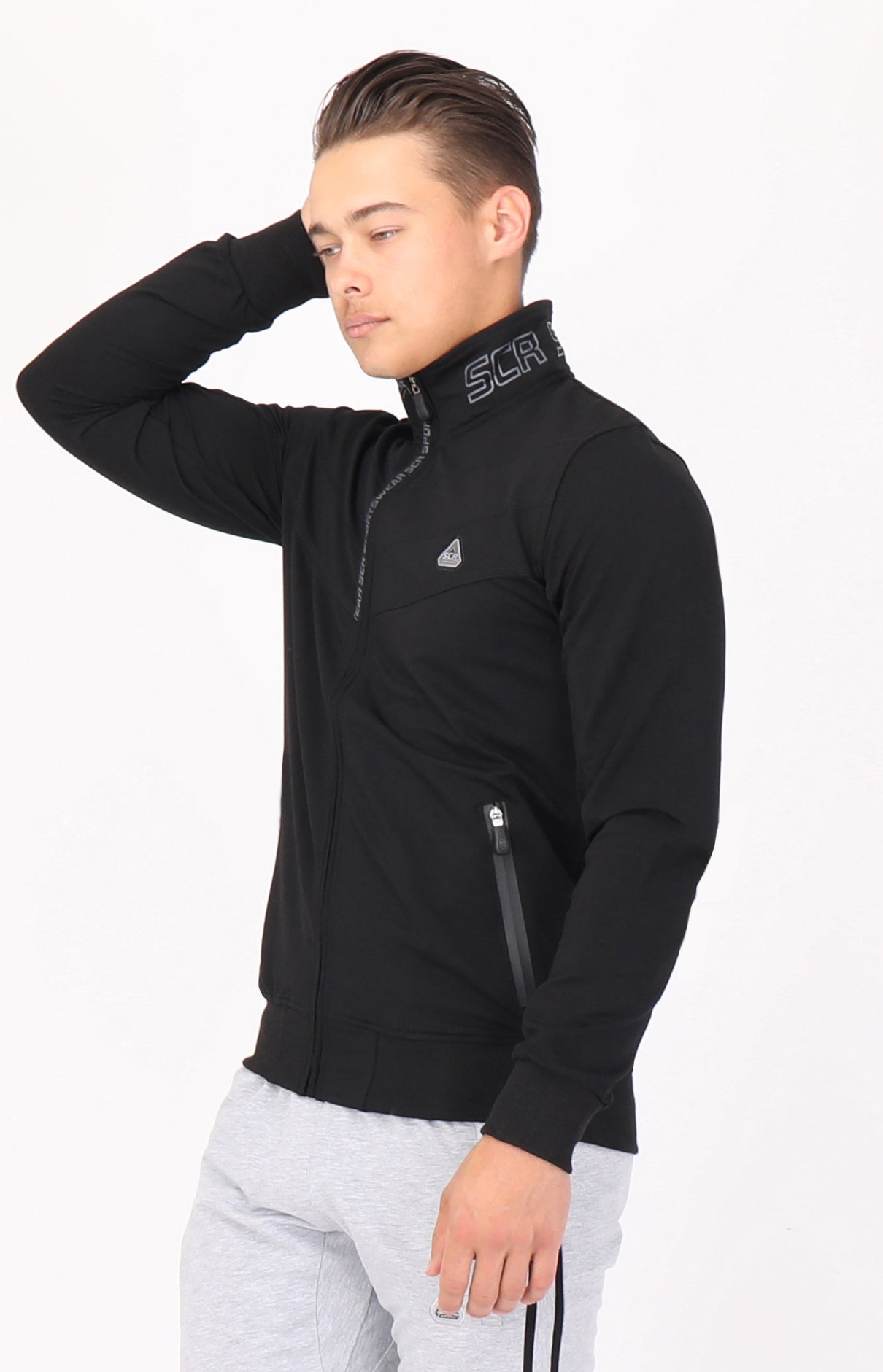 A man wearing a black full-zip athletic sweatshirt with a stand collar, side profile view.