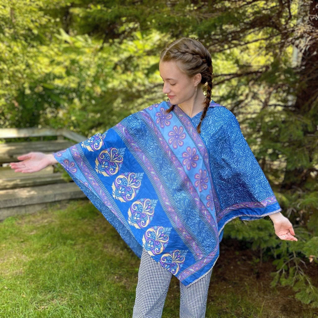 A hand-crafted hooded poncho made from colorful, upcycled sari fabric worn as a fall layer.