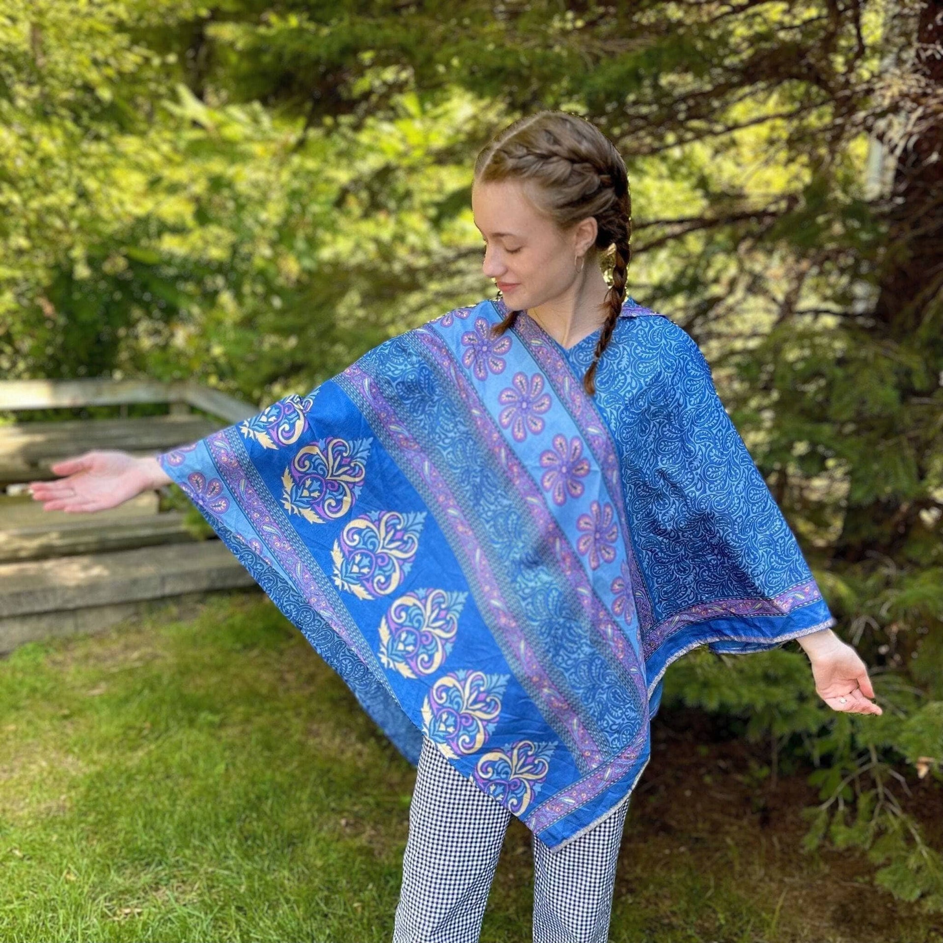 A hand-crafted hooded poncho made from colorful, upcycled sari fabric worn as a fall layer.