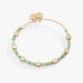 Gold beaded bangle featuring a green four-leaf clover charm and crystal accents