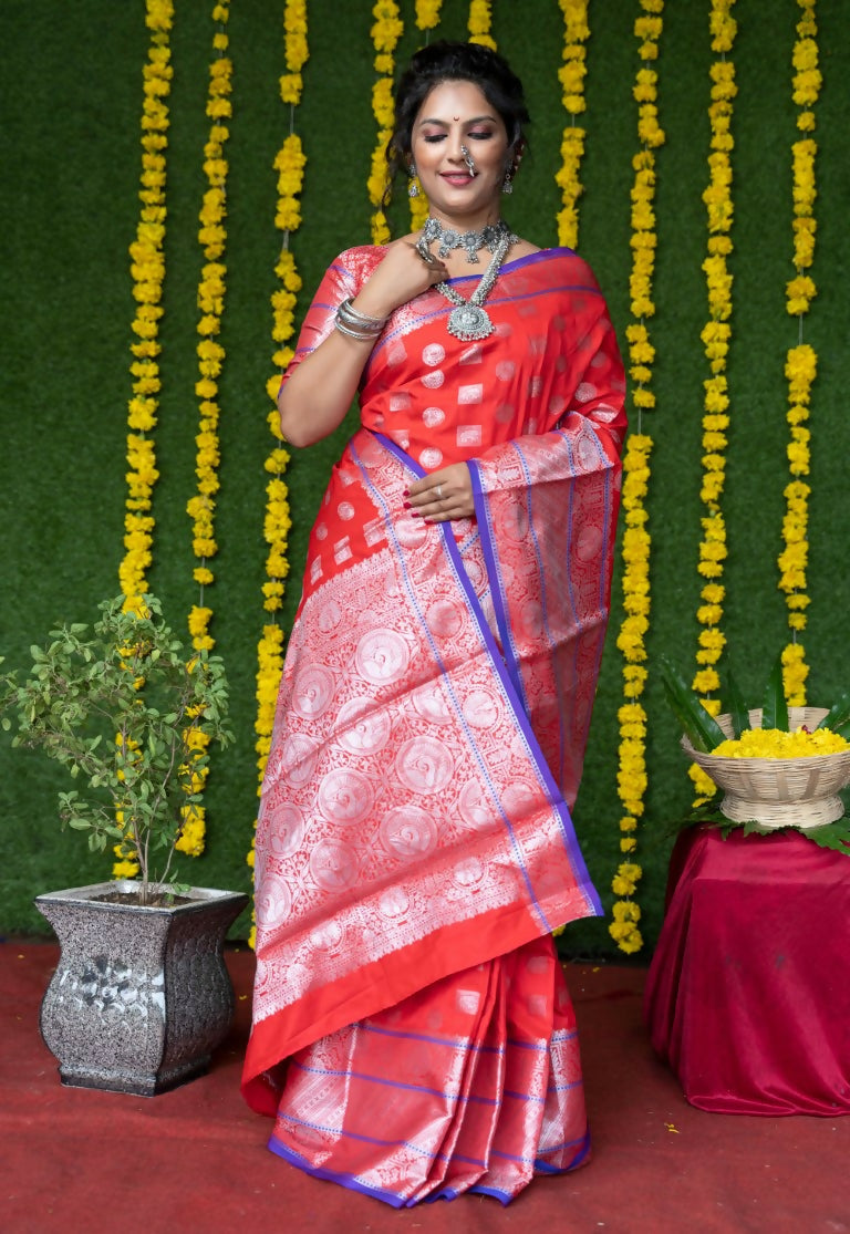 Woman wearing a vibrant red soft handloom silk saree with intricate gold zari woven borders